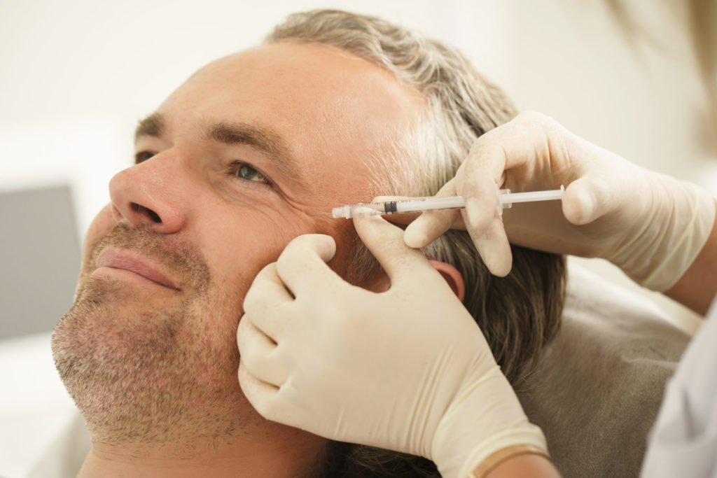 Middle aged male client during filler injections in a clinic